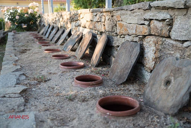 ceramic pots in line, half-burried in the sand at Afianes' winery