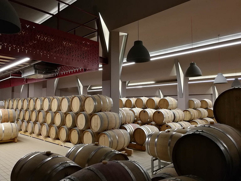 lying wine wood barrels on top of each other at illuminated 'Ktima Kir Yianni' cellar