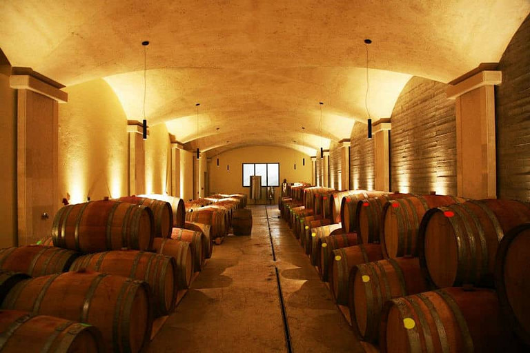 corridor of 'Manousakis Winery' illuminated cellar and on the both sides wine wood barrels on top of each other in a row