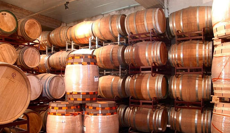 lying wine wood barrels on top of each other at Douloufakis Winery cellar