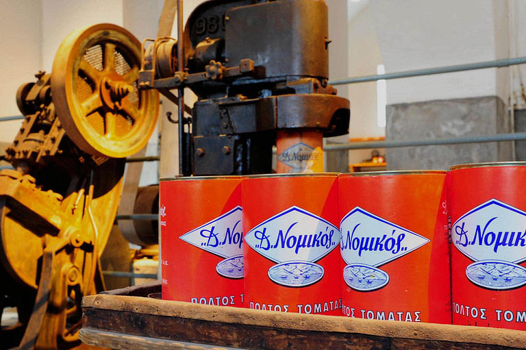 red tin cans with tomato paste and an old machine in the background at 'Tomato Industrial Museum'