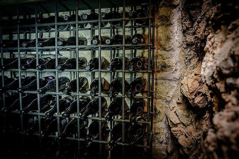 stacked bottles on top of each other in the storage frame on the stone wall at 'Argyriou Winery'