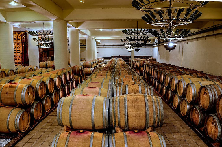 lying wooden barrels in a row on top of each other at 'Semeli Estate' cellar with columns