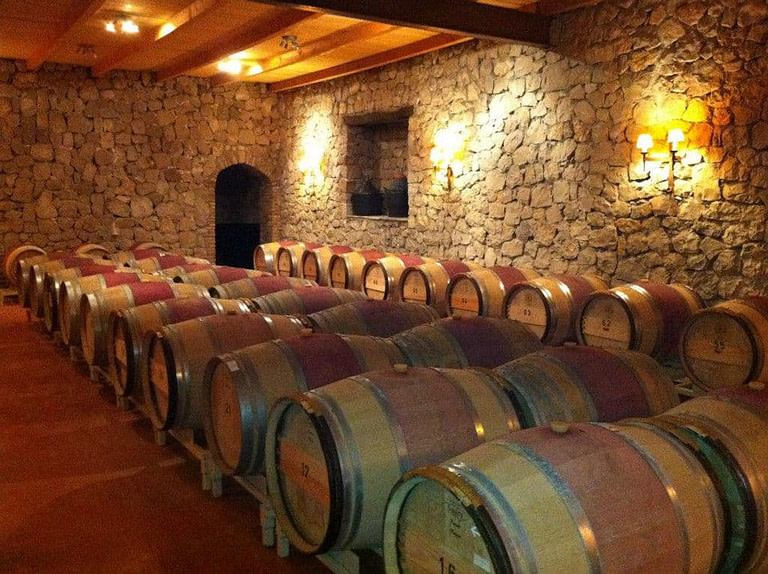 lying wine barrels in a row on the wood panels at 'La Tour Melas' stone cellar