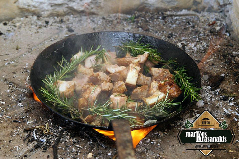 pan with pieces of meat and fresh rosmary that frieding on hot coals on the gtound at 'Markos Krasanakis'