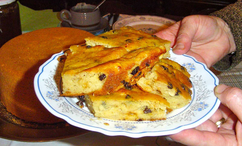 Man holding plate with pieces of ‘Budino’ means pie with semolina, black currants and almonds and showing at the camera