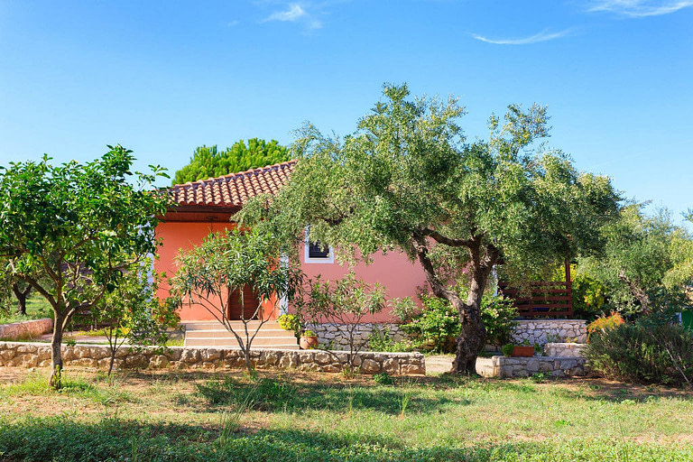 'Lithies Organic Farm' house with pink walls surrounded by trees and green grass