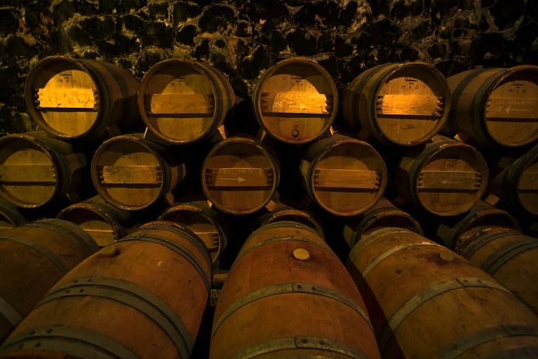lying wine wood barrels on top of each other at 'Dourakis Winery' cellar