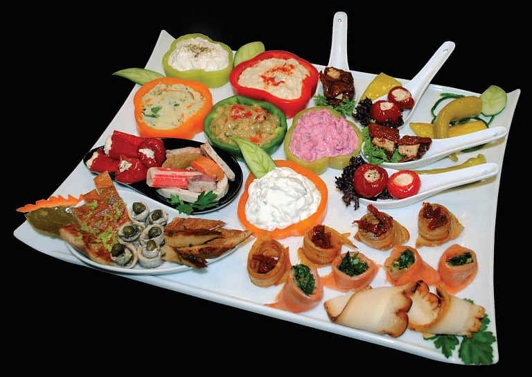 plate with various aperitifs from 'Pitenis' like stuffed peppers with salade and mayonnaise or pickles