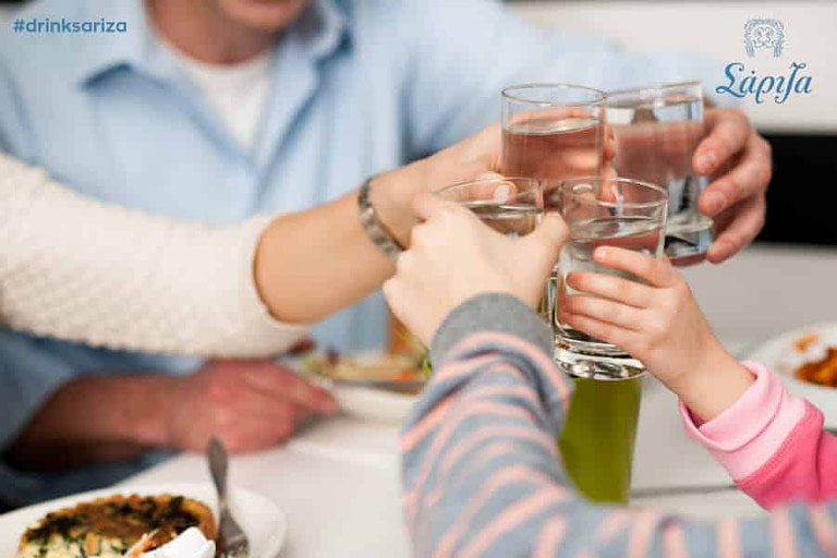 two childs and their parents clink glasses of water for 'cheers' from 'Sariza Water'
