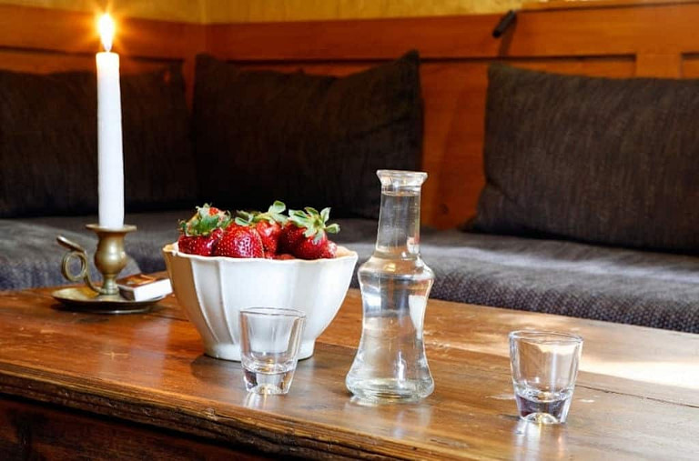 a bottle and two glasses with raki and a bowl with fresh strawberries on the table of 'Milia Mountain Retreat'