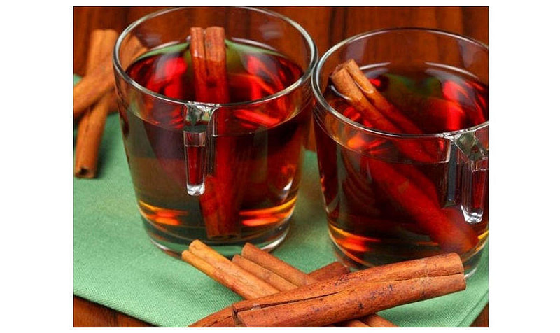close-up of cinnamon sticks in two glasses with ‘kanelada’ red drink and surrounded it