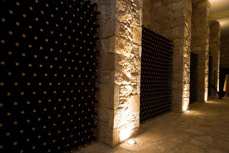 wine bottles on top of each other storaged in the stone wall in 'Kellari Papachristou' cellar