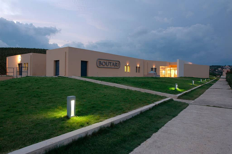 one side of the building with green lawn of Boutari Crete Winery by night