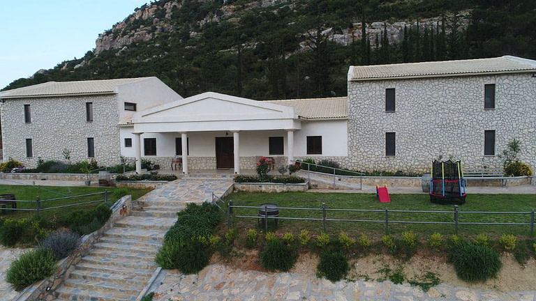 front view of 'Ktima Karamitsos' building with stone steps and green lawn on the both sides
