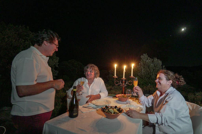 a couple having a romantic dinner under the moonlight and talking with a man of Afianes' winery