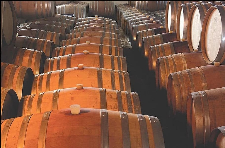 lying wine wood barrels someone on top of each other in a row at 'Domaine Dereskos' cellar