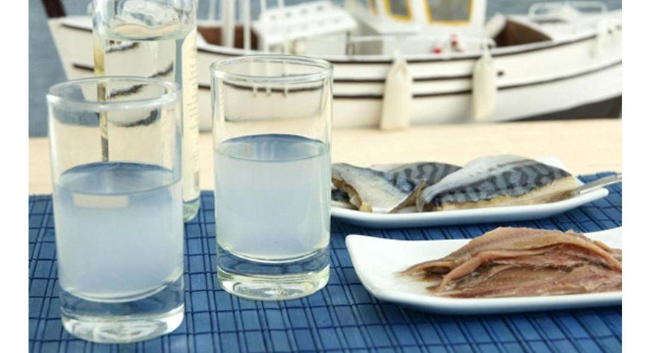 Close-up of glasses with Greek ‘Ouzo’ and plates with marinated fish