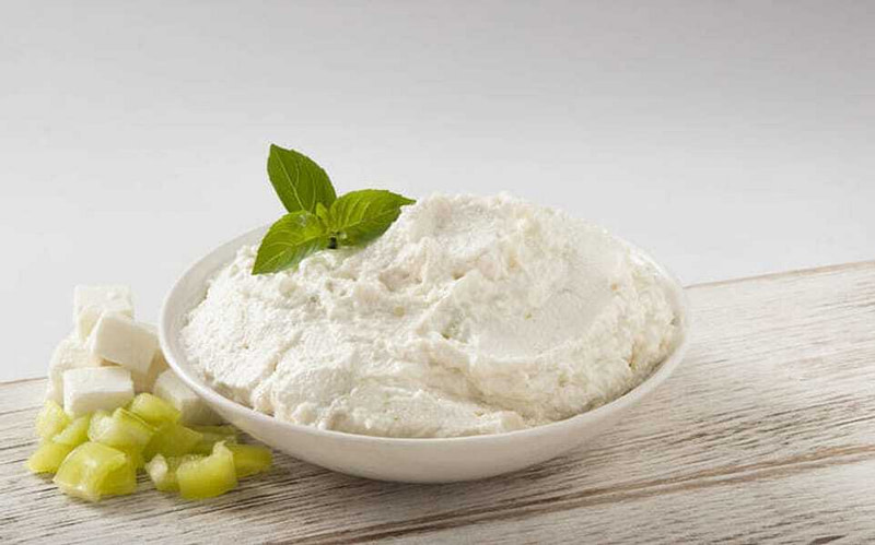 Bowl with Greek ‘Tirokafteri is a cheese-based spread with fresh green leaves on top