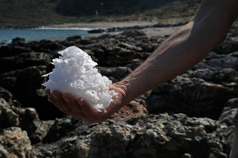 man holding salt from the rocks at the sea coast in 'Astarti' area