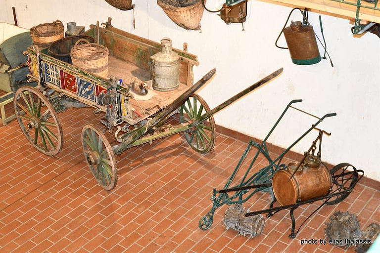 old hand painted wooden horse cart with four wheels and hanging wicker baskets on the wall at Tzivani Bio Wines