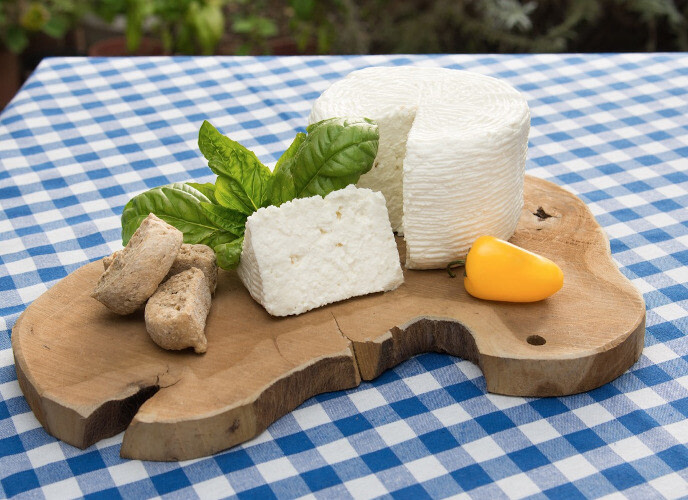 close-up of pieces of Greek ‘Kalathaki of Lemnos’ is a white, briny, wheel-shaped cheese and dry breads on wooden platter