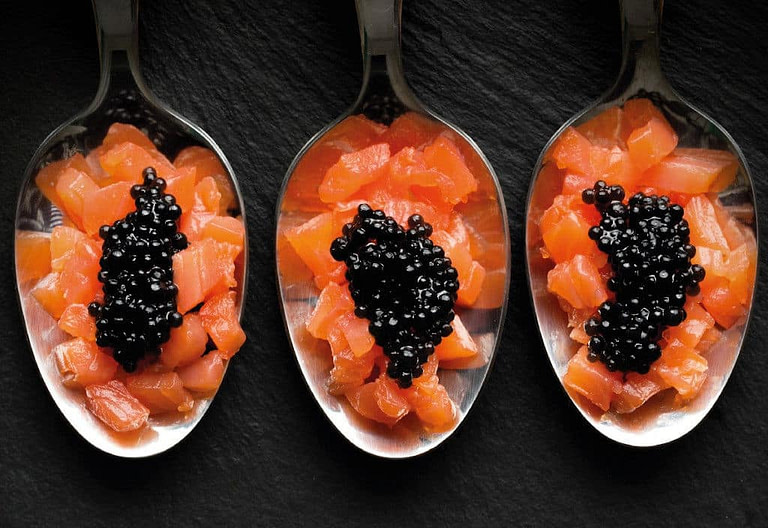three spoons with pieces of boiled carrots and black caviar eggs on top from 'Thesauri Caviar'